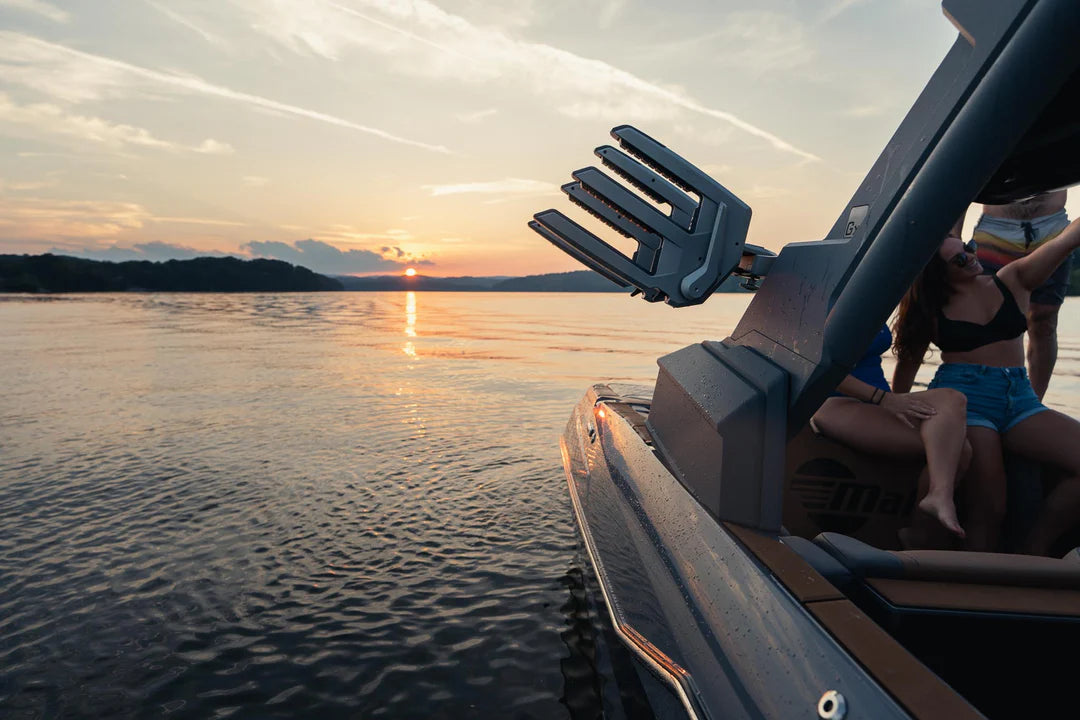 Close-up of CLAMPFORCE 3.0 Board Racks mounted on a boat, with a sunset over a calm lake in the background.