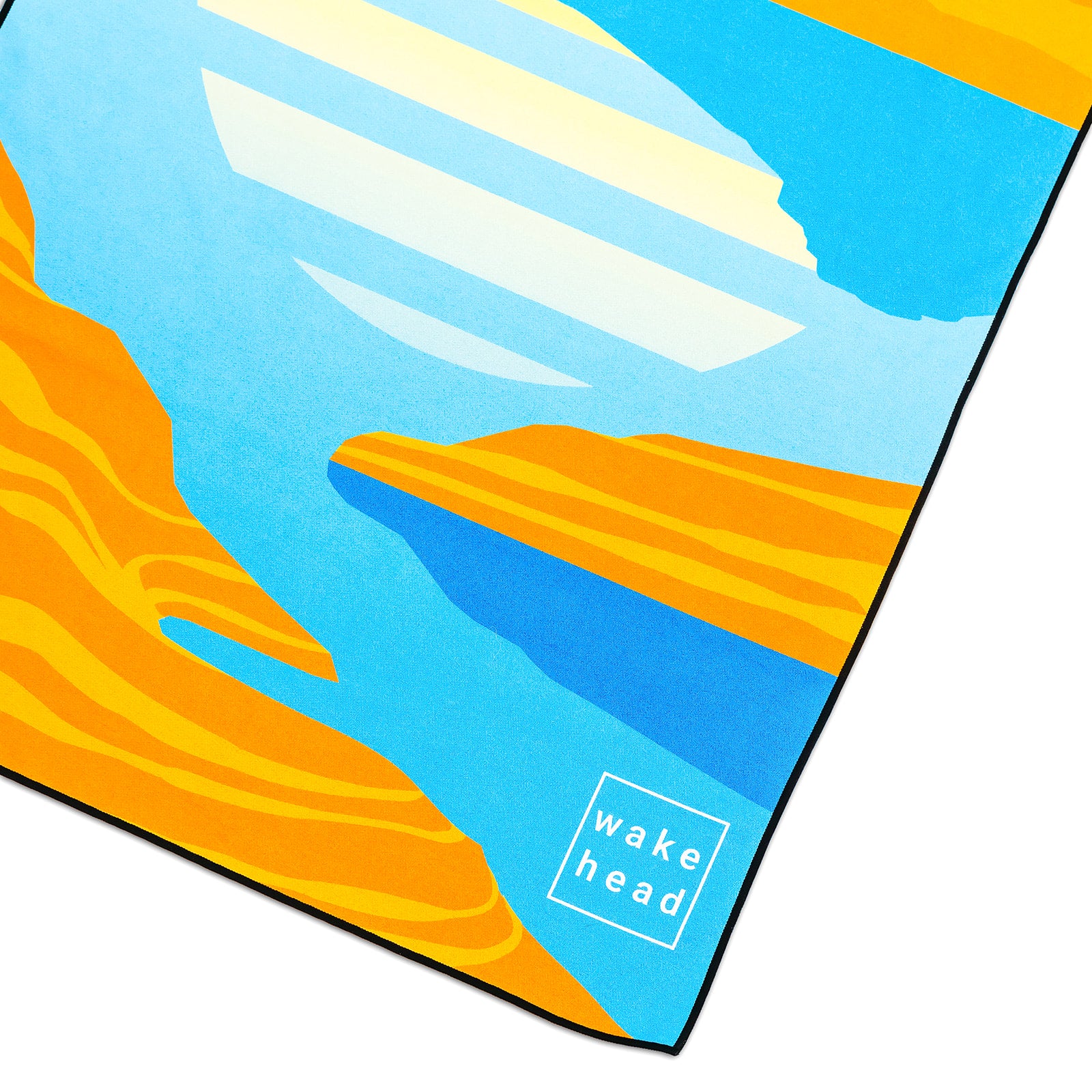 Close-up of a colorful Powell Towel with abstract orange, blue, and yellow design, featuring the "Wake Head" logo in the corner.